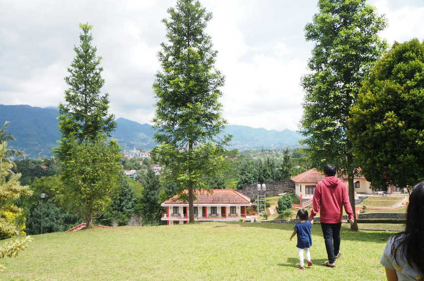 Father and child walking on open field with the mountain view