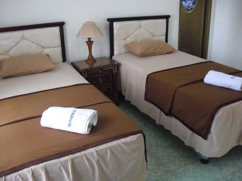 Guest room comprised of two single beds with brown bed cover and white bed sheet